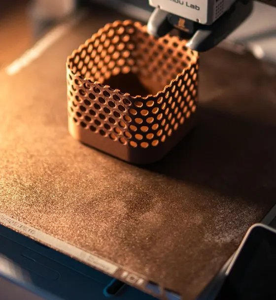 Canasto de cobre con perforaciones hexagonales a medio imprimir en 3D